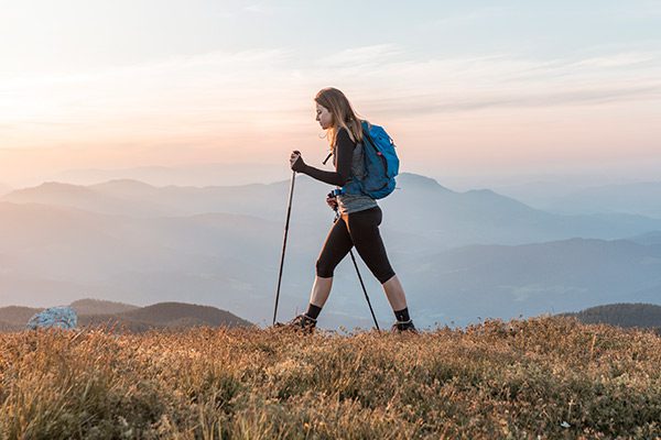Woman hiking with poles across mountainous scenery