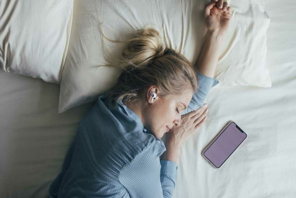 Woman sleeping with smartphone beside her